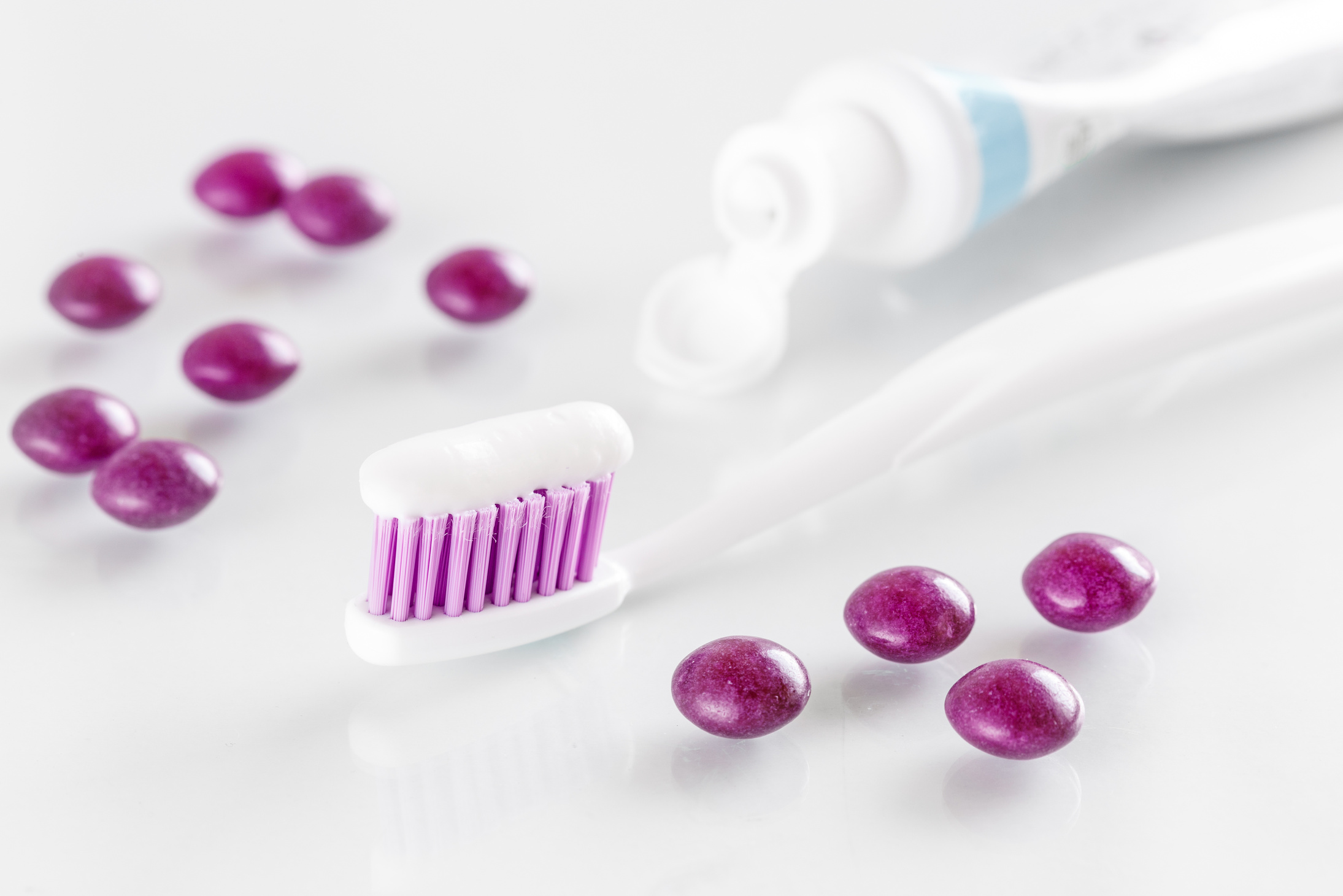 sqweezed purple toothbrush on white background with candies