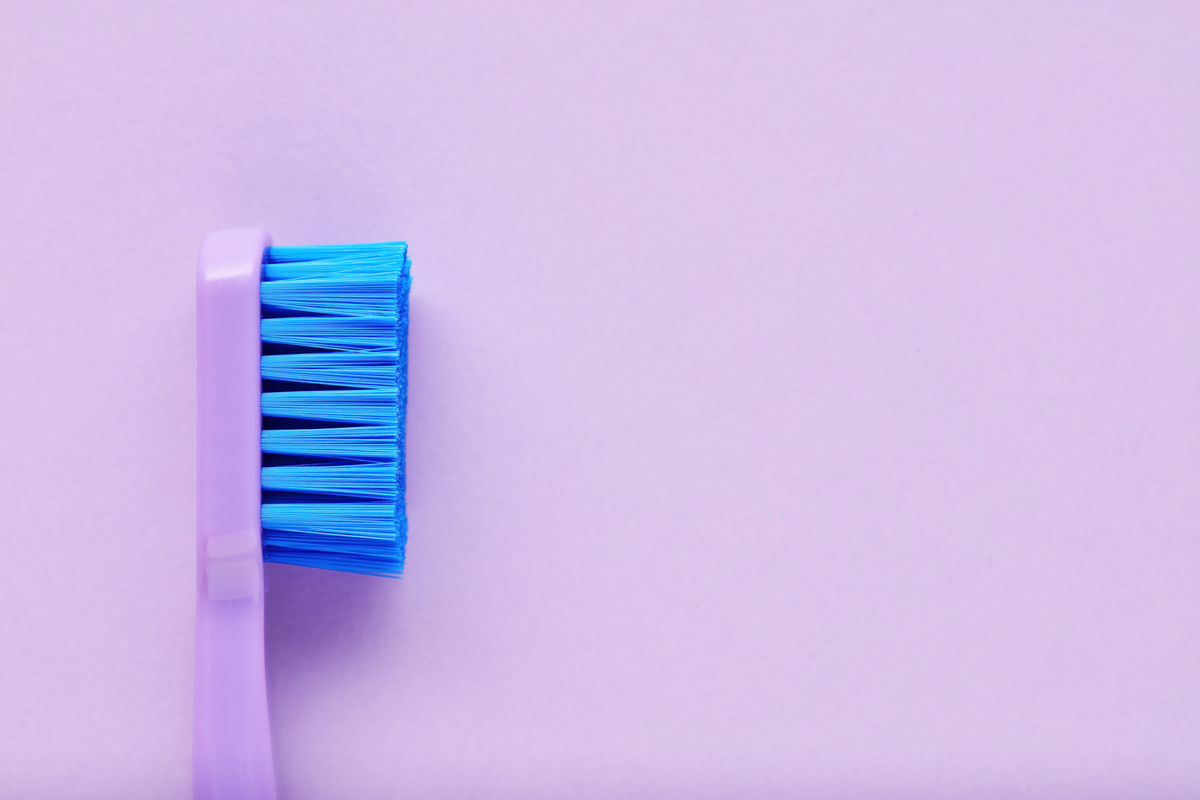 Close up side view of a new purple toothbrush on purple background