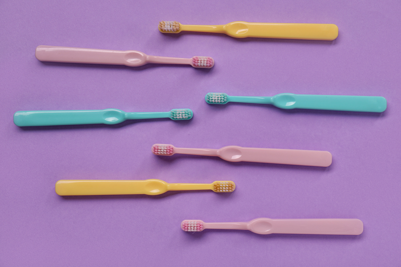 Many Plastic Toothbrushes on Purple Background